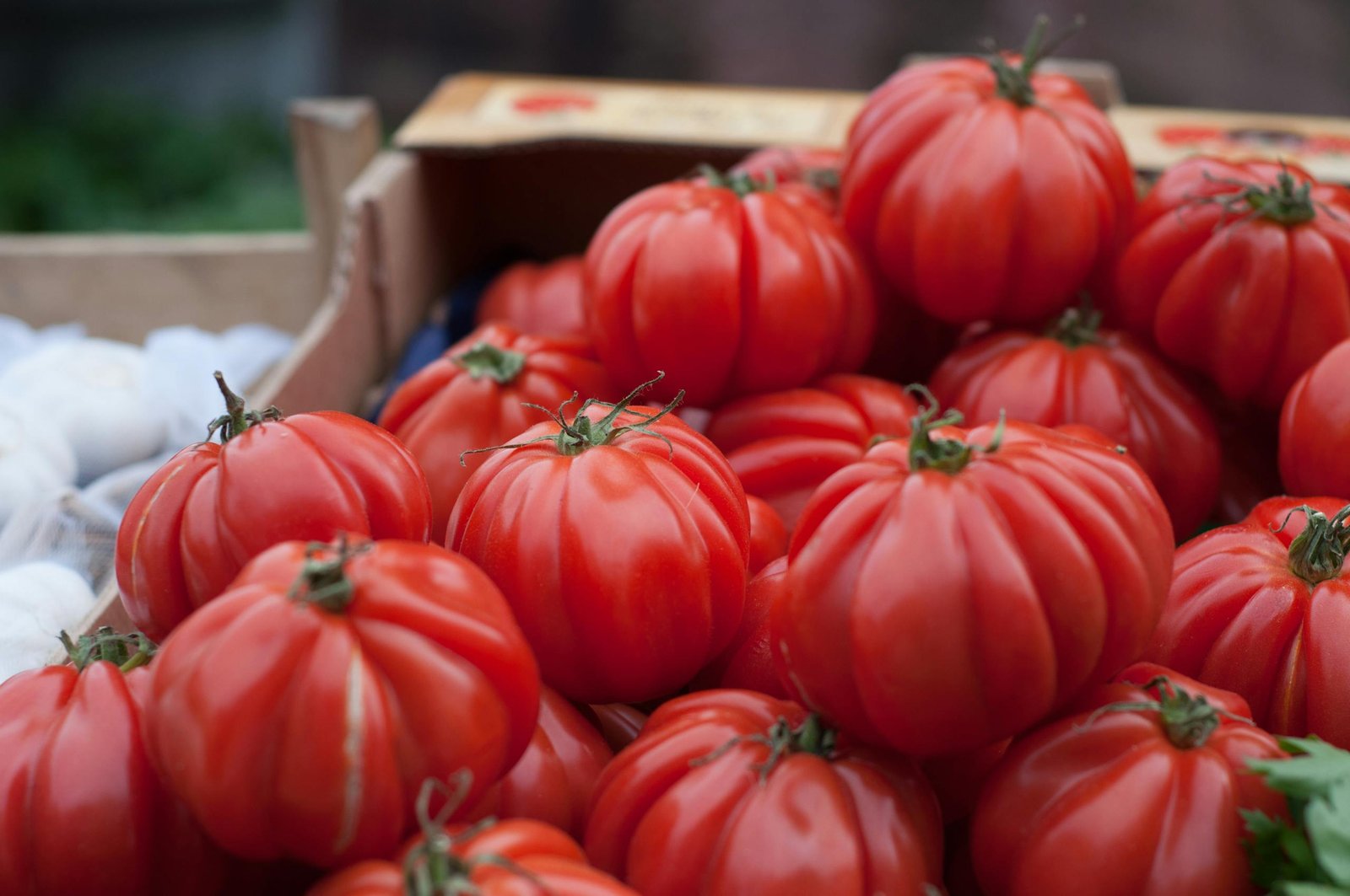 A close-up of vibrant red heirloom tomatoes on display at a market stand.