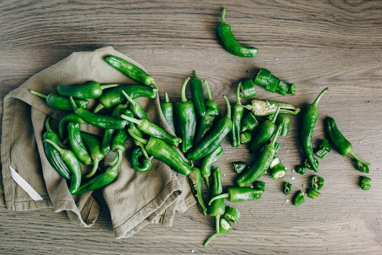 Serrano Peppers: A Beginner’s Guide to Growing Serrano Peppers 9 A flat lay of fresh green chilies on a wooden surface with a cloth.